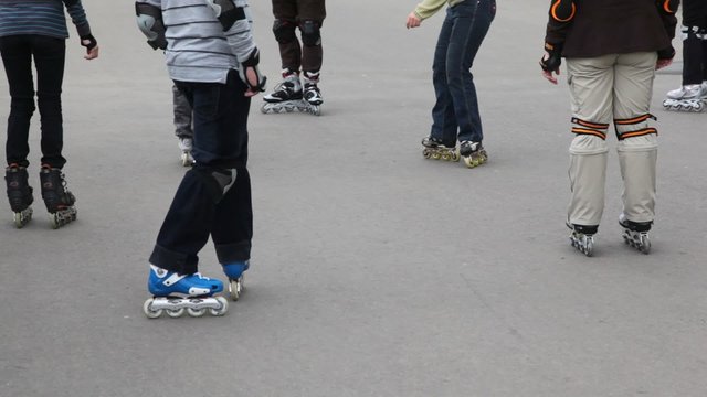 legs of unidentified kids in roller skates on asphalt
