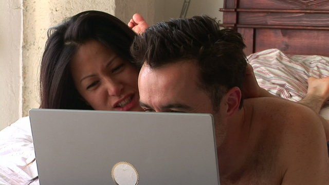 Young couple in bed with Young couple in bed with laptop