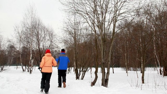 man and woman run on snow aside winter birch forest, then back