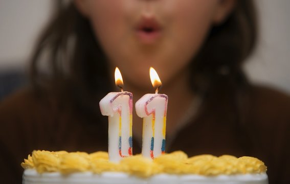 Girl Blowing Out Candles On A Birthday Cake