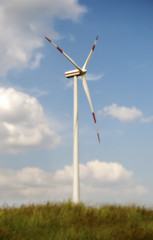 Wind turbine at blue sky with clouds