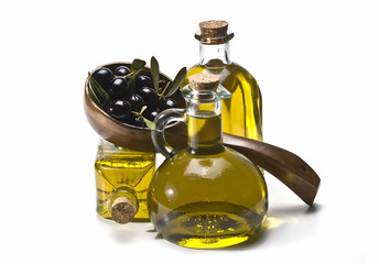 Cucharón con aceitunas y botellas con aceite de oliva.