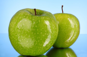 Two green apples on blue background