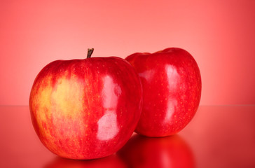 Two red apples on red background