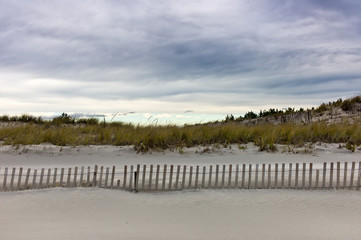 Fenced sand dunes on beach on Long Island, NY with cloudy sky - 28741846