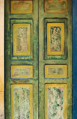 Old wooden door with fading green and yellow paint