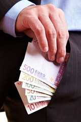 Hand steckt Geld in Hosentasche