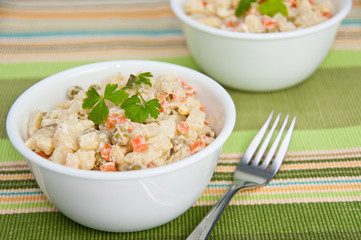 Two bowls of potato salad and a fork on on green napkin