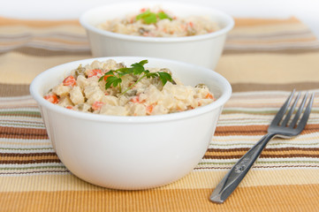 Two bowls of potato salad and a fork on yellow napkin