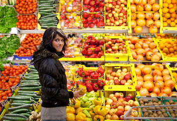 Beautiful young woman buying fruits and vegetables at a produce