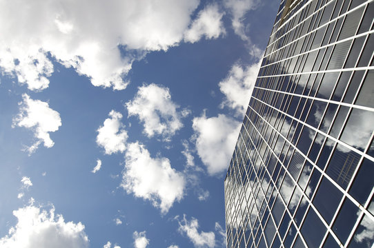 Modern office building with cloud reflection in window.
