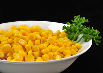 Mais - Maiskörner mit Petersilie auf weißem Teller