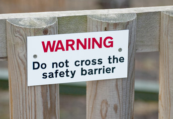 warning sign screwed to wooden fence