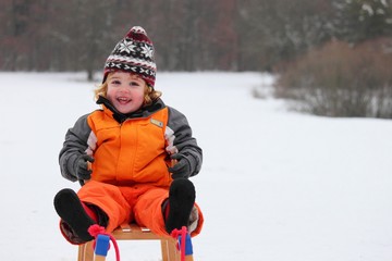Fototapeta na wymiar Kind beim Schlittenfahren im Winter