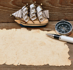 old paper, compass, rope and model classic boat on wood backgrou