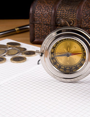compass, pen and coin on notebook