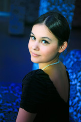Beautiful Asian girl in a black dress in glamorous dark interior
