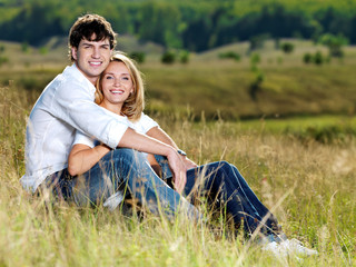 Naklejka na ściany i meble beautiful couple sitting in meadow