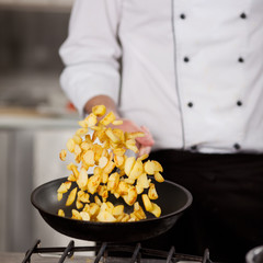 koch wendet bratkartoffeln in der pfanne