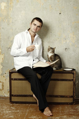 Man on the suitcase is drinking coffee and reading the newspaper