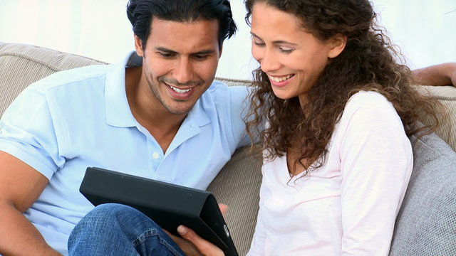 Couple using a computer tablet sitting on the couch
