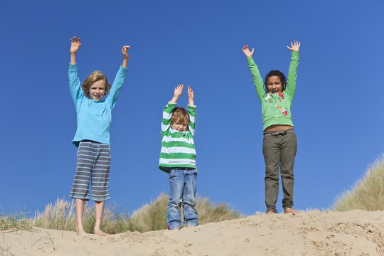 Three Children Arms Raised Having Fun on Beach