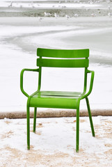 An empty green chair in a park in winter