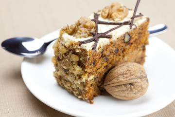 Fototapeta na wymiar Piece of cake with nuts and spoon lying on a plate