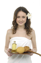 Young woman holding a tray with lotion and washtub, white towels