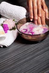 Human hands in bowl with oil and chrysanthemum flower