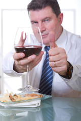 man with thumb up at restaurant with glass red wine