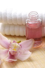 Obraz na płótnie Canvas Spa essentials (white towel and pink orchids with massaging oil)
