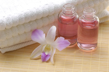 Obraz na płótnie Canvas Spa essentials (white towel and pink orchids with massaging oil)