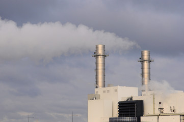 Power plant chimneys with clouded and smoky sky