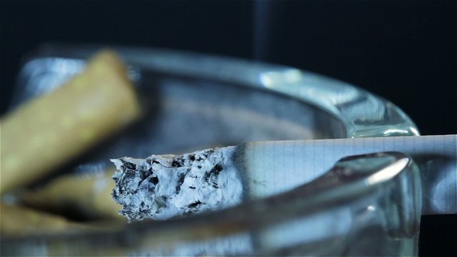 Qualmende Zigarette im Aschenbecher als Makro