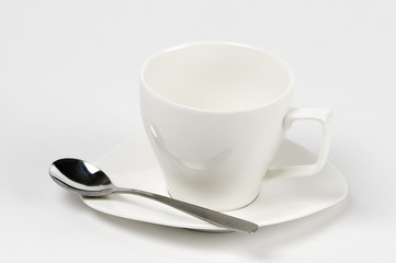 Taza blanca de café  vacía con plato y cuchara