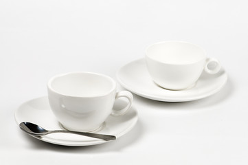 Dos Tazas  blancas  de café  vacía con plato y cuchara