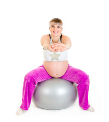 Smiling beautiful pregnant woman doing exercises on ball