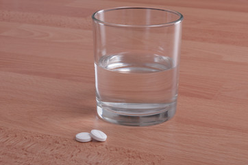 Aspirins tablets and water on desk