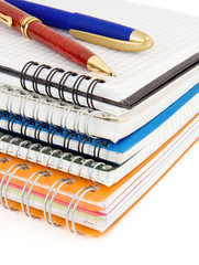 pens on checked notebook isolated on white