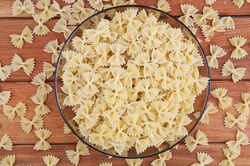 Raw farfalle in glass plate top view