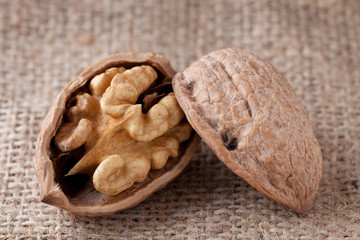 Macro cracked walnut, kernel inside, nutshell on sackcloth backg