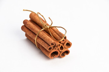 Cinnamon sticks with gold ribbon on white background