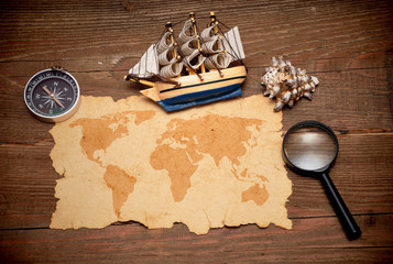 model classic boat, compass and loupe on wood background
