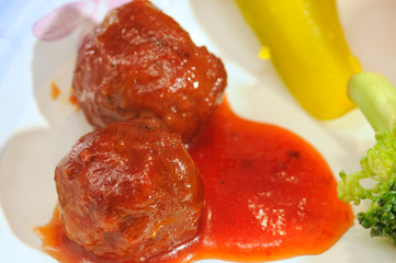 Meatballs and sauce on a plate with pickle