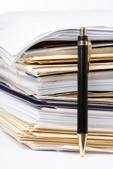 a pen near stack of paper