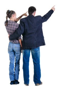 Young couple pointing at wall. Rear view.