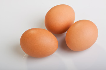 Three brown eggs on white background