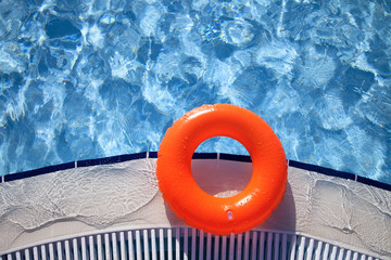 floating orange ring on edge of swimpool with waves reflecting i