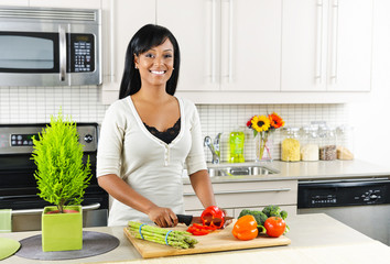 Young woman cutting vegetables in kitchen - Powered by Adobe
